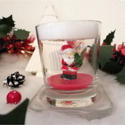 Bougie de Noël avec un Père Noël posé sur de la cire rouge et un toit de cire blanc au-dessus